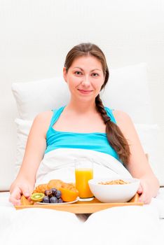 a woman with a tray of breakfast in bed in the morning