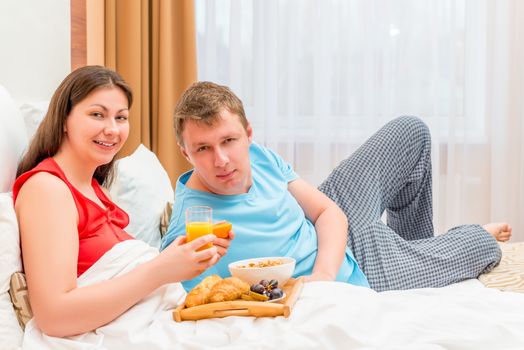 happy young family eating breakfast in bed