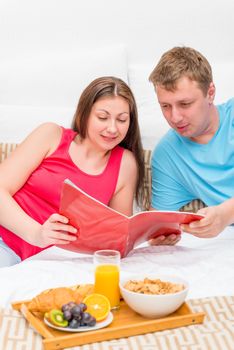 woman and man looking a magazine in bed in the morning