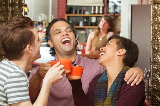 Happy group of three diverse adults laughing with coffee cups