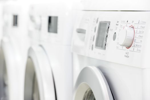 row line of modern white laundry washing machines