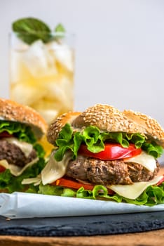 Closeup of Homemade Hamburger with Fresh Vegetables and Drink with Ice in Background