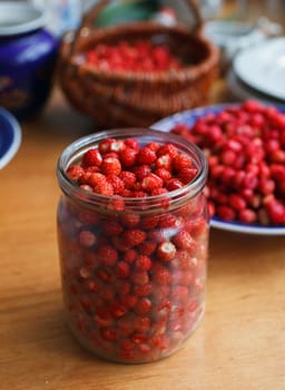 Fresh ripe wild strawberries in a jar on a wooden table