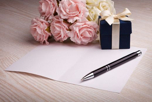 blank card with pen, blue gift box, pink and white roses 