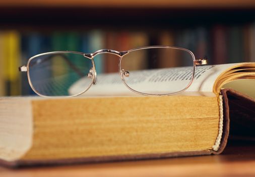 glasses and book on background bookcase