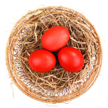 Red Easter eggs in a straw nest isolated
