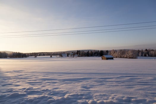 A barn and a big field of snow in the foreground