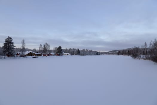 A frozen river with some homes alongside it