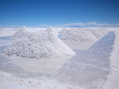 Piles of drying salt and reflection in the water at the Salar de Uyuni (salt flats) in Bolivia.