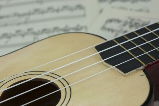 Close up of a ukulele rested on sheet music