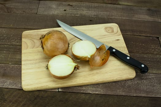 Onion on a wooden chopping board with knife