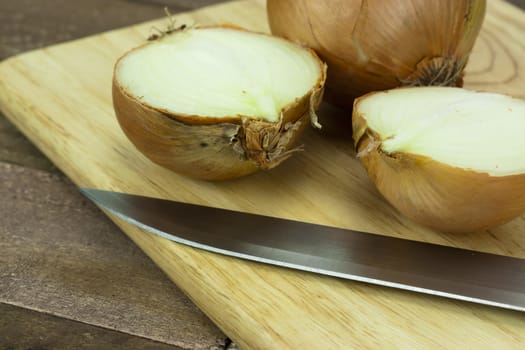 Onion on a wooden chopping board with knife