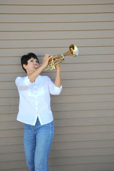 Mature female beauty blowing her trumpet outside.