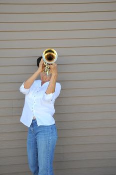 Mature female beauty blowing her trumpet outside.