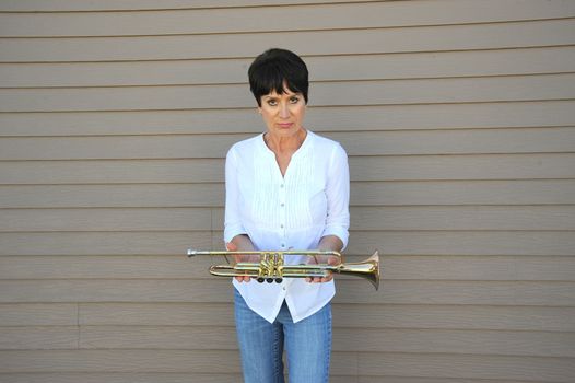 Mature female beauty blowing her trumpet outside.