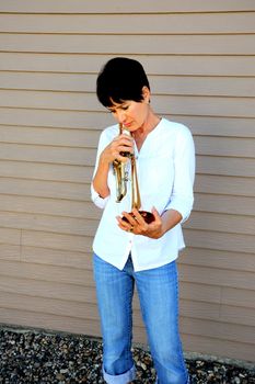 Mature female beauty blowing her trumpet outside.