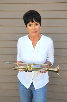 Mature female beauty blowing her trumpet outside.