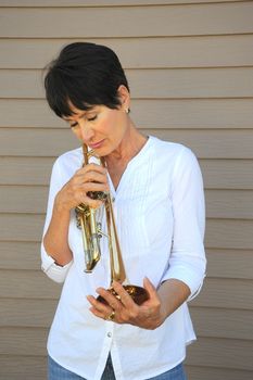 Mature female beauty blowing her trumpet outside.