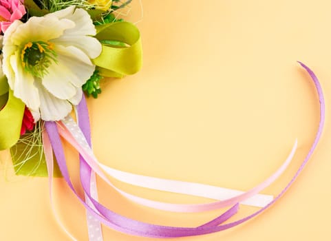 artificial flowers and streamers on cream background with place for label relamy