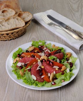 Salad of grapefruit and persimmon in lettuce leaves with cashews, almonds, pomegranate