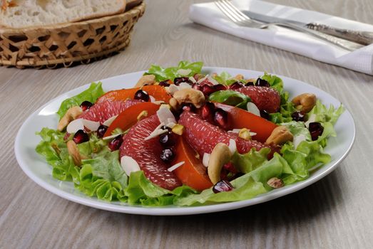 Salad of grapefruit and persimmon in lettuce leaves with cashews, almonds, pomegranate