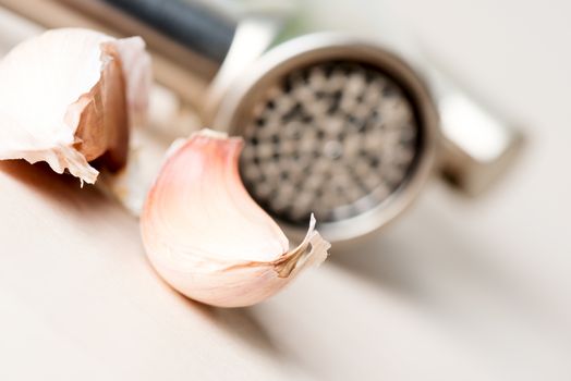 Garlic and garlic press on wooden table