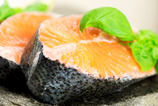 Salmon cuts on stone with basil and lemon macro