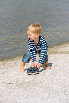 Little preschool boy playing on shore outdoors