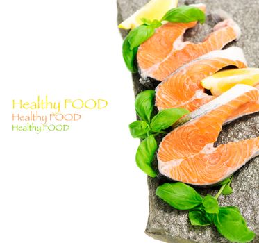 Salmon cuts on stone with basil and lemon isolated on white, copy space