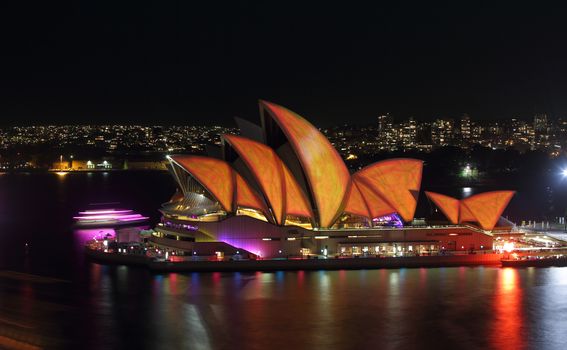 SYDNEY, AUSTRALIA - MAY 27, 2015; The Sydney Opera House comes alive each night during Vivid Sydney.  Coloured lights and patterns shine on the roof creating a spectacular event.  Here the roof alight in vivid orange and yellow from a 20 second exposure of various imagey