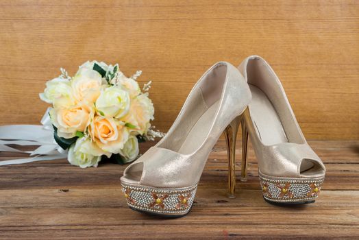 Wedding bouquet with bride's shoes on wood floor background