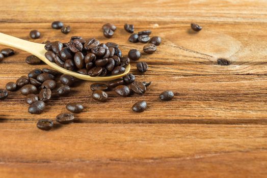 Coffee bean on wooden spoon and wooden table background