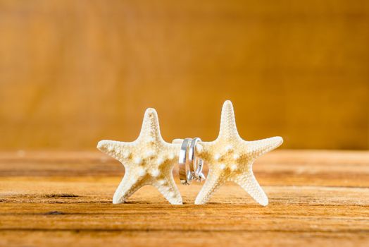 Two wedding rings with two starfish on wooden table, vintage wedding look