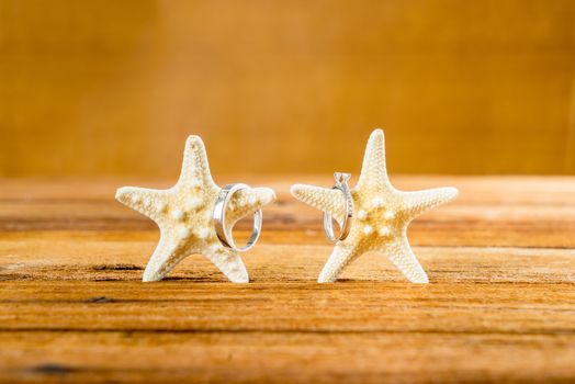 Two wedding rings with two starfish on wooden table, vintage wedding look