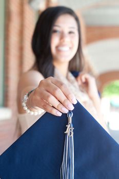 Outdoor shot of attractive high school graduate holding graduation gown.