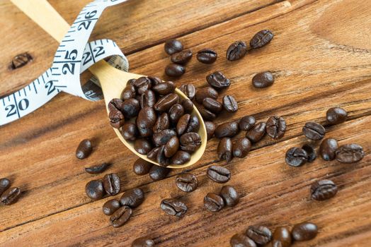 Coffee bean on wooden spoon and tape measure on wooden table background