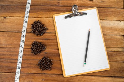 Wooden Clipboard attach planning paper with pencil on top beside coffee bean, tape measure