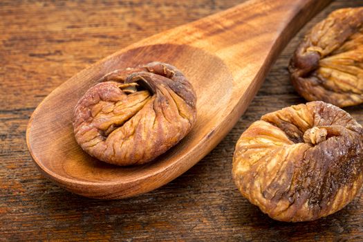 dried Turkish figs on a wooden spoon against rustic wood