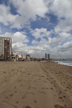 A beach with a lot of tracks in the sand with a cloud filled sky