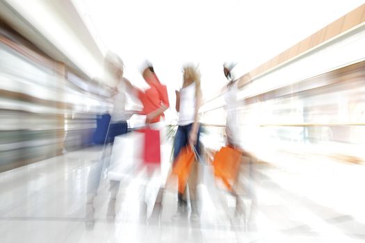 Women walking fast in shopping mall with bags