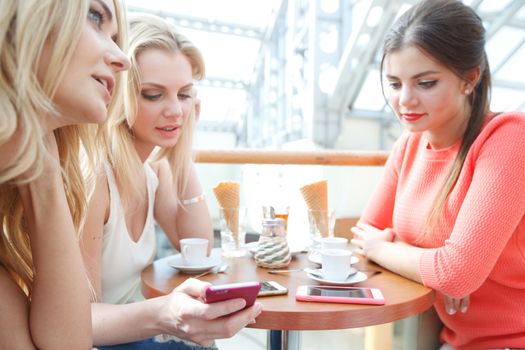Group of young women sitting in cafe with gadgets