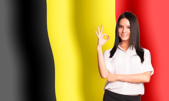 Smiling woman showing ok on Belgium flag background