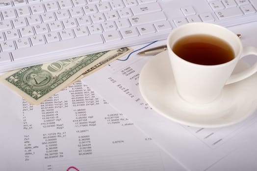 White keyboard with coffee cup, dollars and documents