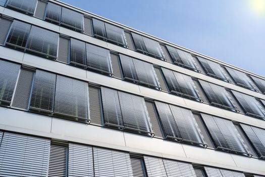 Facade of modern high-rise office building with covered windows Venetian blinds against blue sky