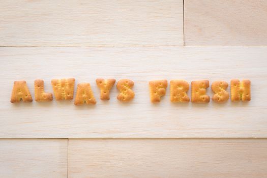 Close up the set of  character word ALWAYS FRESH. Alphabet biscuit crackers putting on piece of wood background.