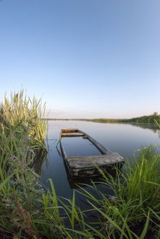 Old sunken wooden boat on the lake