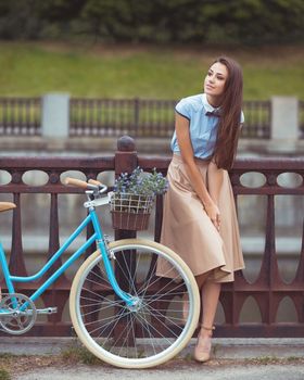 Young beautiful, elegantly dressed woman with bicycle. Beauty, fashion and lifestyle