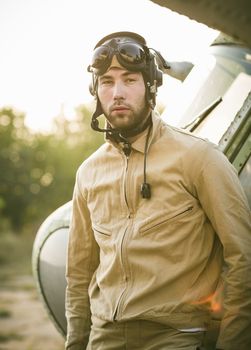 Young serious pilot posing near the helicopter