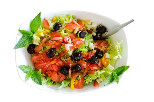 Isolated fresh plain salad garnished with sprigs of mint containing lettuce, tomato, sweet peppers and black olives served in a bowl with a fork