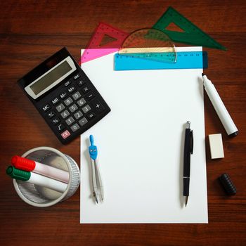 Desk with sheet of paper and stationery objects seen from above